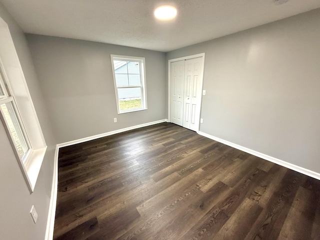 unfurnished bedroom with dark hardwood / wood-style flooring and a closet