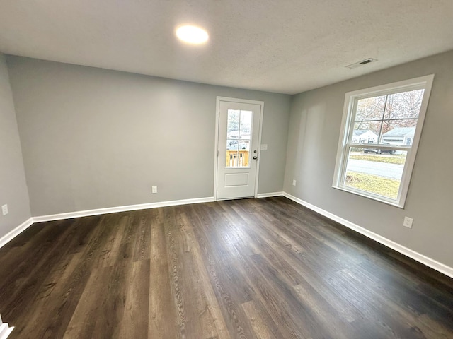 unfurnished room featuring dark hardwood / wood-style flooring and a textured ceiling