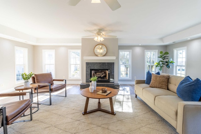 living room with light hardwood / wood-style floors, ceiling fan, and a premium fireplace