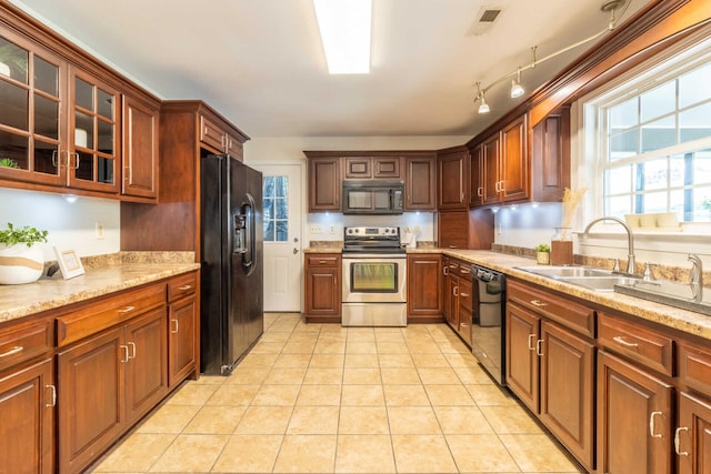 kitchen featuring light stone counters, sink, light tile patterned floors, and black appliances