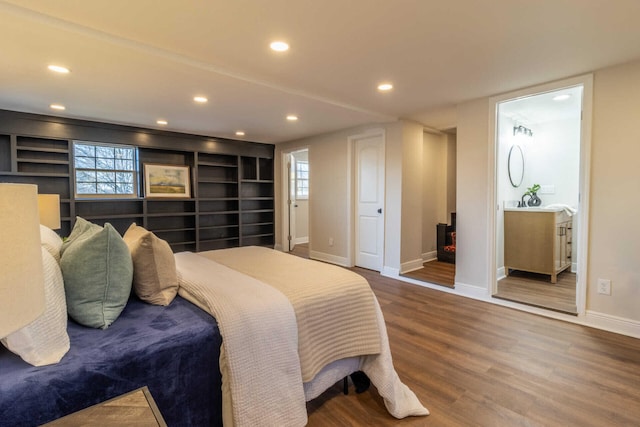 bedroom with hardwood / wood-style flooring, a wood stove, and multiple windows