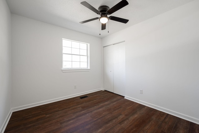 empty room featuring ceiling fan, dark hardwood / wood-style flooring, and a textured ceiling