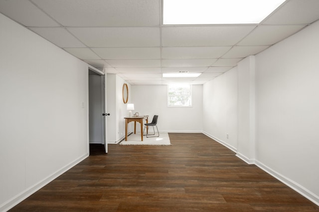 basement with a paneled ceiling and dark wood-type flooring