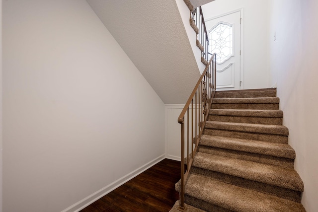 stairway featuring hardwood / wood-style flooring and lofted ceiling