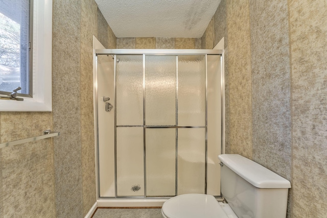 bathroom featuring a textured ceiling, toilet, and walk in shower