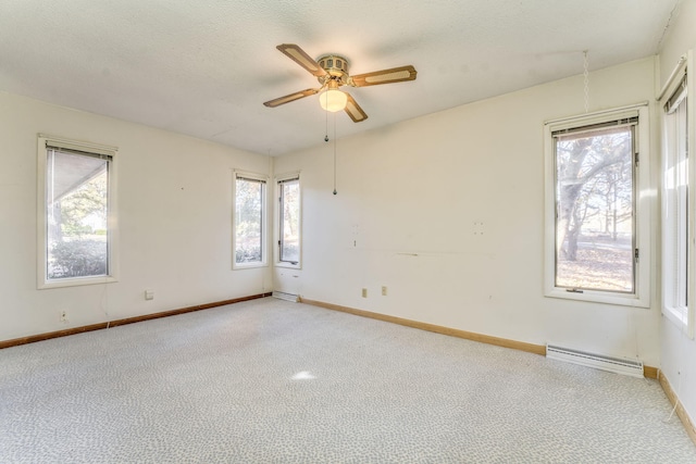 empty room with a wealth of natural light, a baseboard heating unit, and ceiling fan