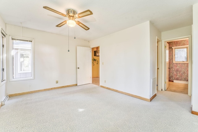 carpeted empty room with ceiling fan, a healthy amount of sunlight, and a textured ceiling