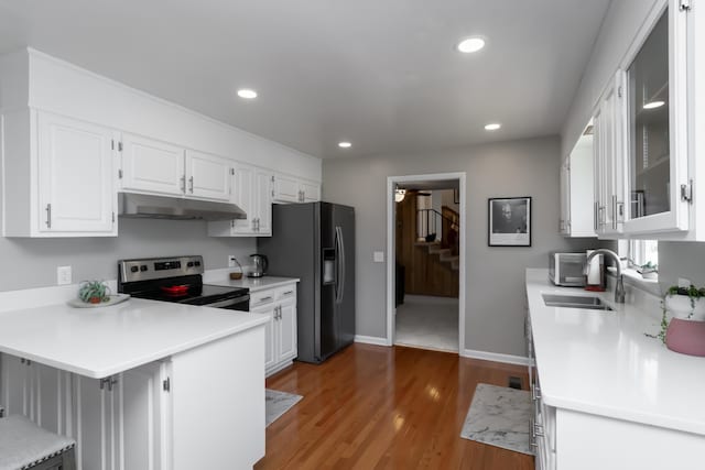 kitchen with a kitchen bar, appliances with stainless steel finishes, kitchen peninsula, sink, and white cabinets