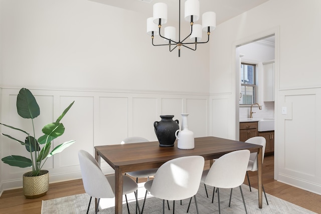 dining space featuring sink, light hardwood / wood-style flooring, and a notable chandelier