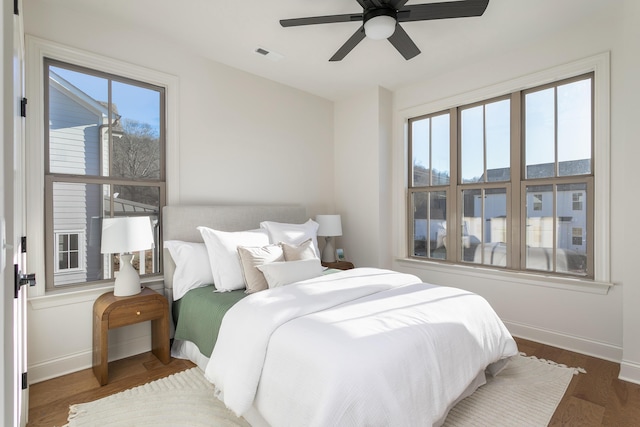 bedroom with multiple windows, ceiling fan, and dark hardwood / wood-style flooring