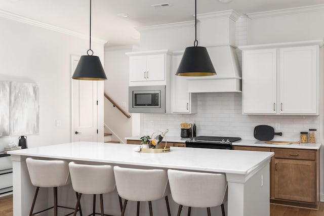 kitchen with stainless steel microwave, decorative backsplash, black / electric stove, a kitchen island with sink, and white cabinets