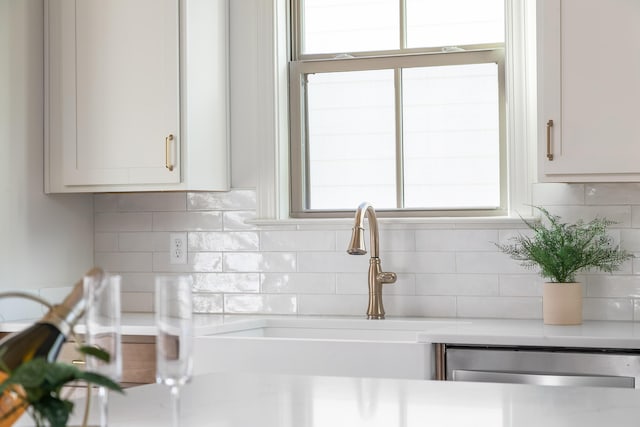 room details featuring dishwasher, decorative backsplash, white cabinetry, and sink