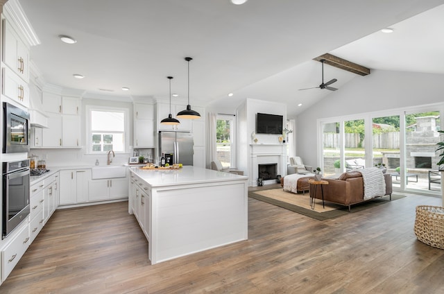 kitchen featuring pendant lighting, white cabinets, a kitchen island, beam ceiling, and stainless steel appliances