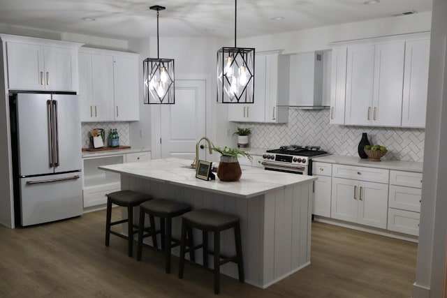 kitchen with white cabinets, high end appliances, dark hardwood / wood-style flooring, wall chimney range hood, and a kitchen island with sink