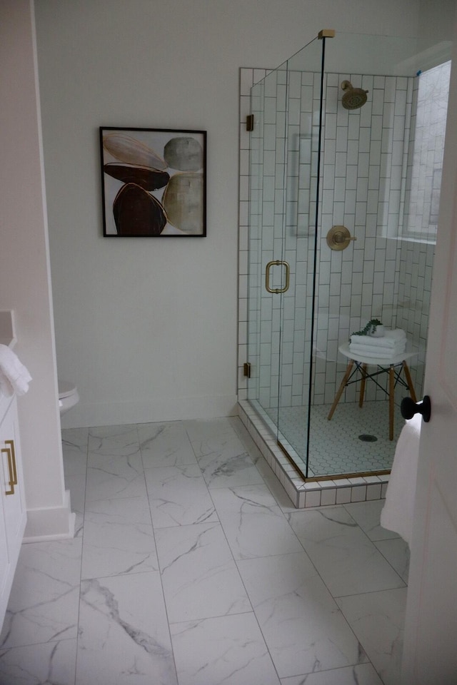 bathroom featuring a shower with door and toilet