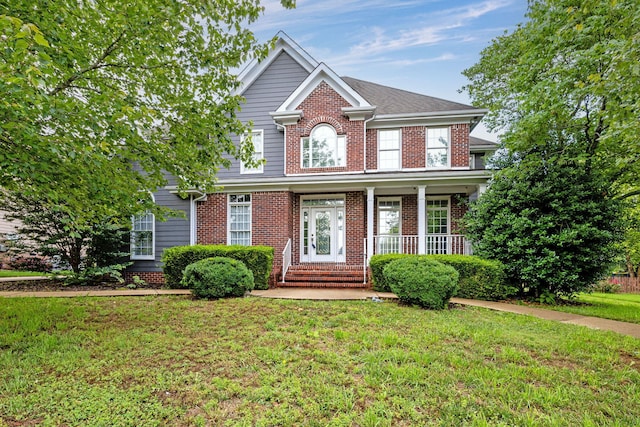 colonial inspired home with covered porch and a front yard