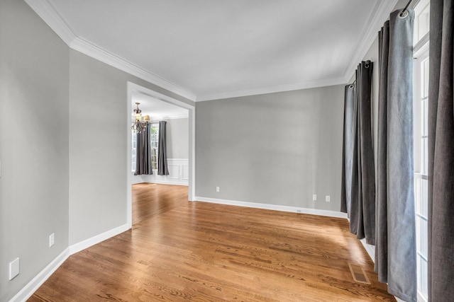 unfurnished room with hardwood / wood-style flooring, a notable chandelier, and ornamental molding