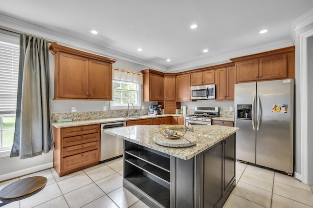 kitchen featuring light stone counters, stainless steel appliances, sink, a kitchen island, and light tile patterned flooring