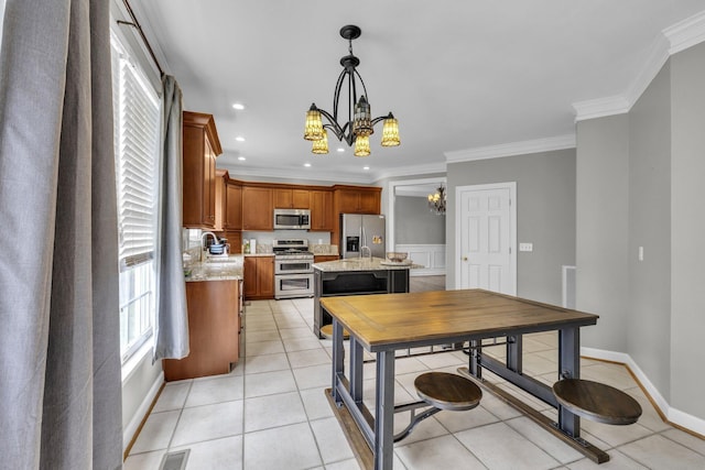 kitchen with a center island, hanging light fixtures, ornamental molding, stainless steel appliances, and a chandelier