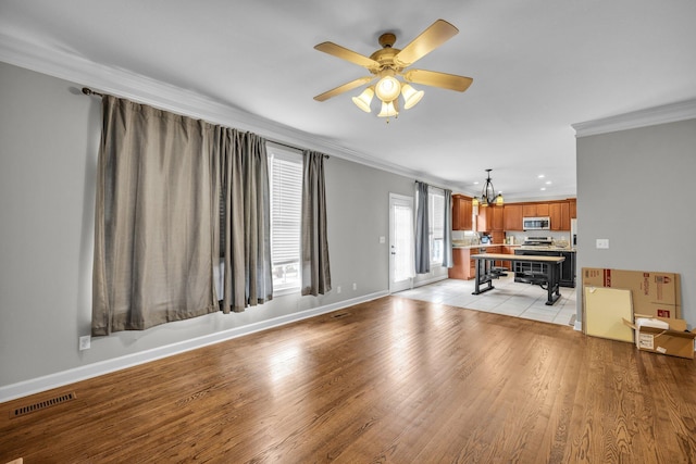 living room featuring ceiling fan with notable chandelier, light wood-type flooring, and crown molding