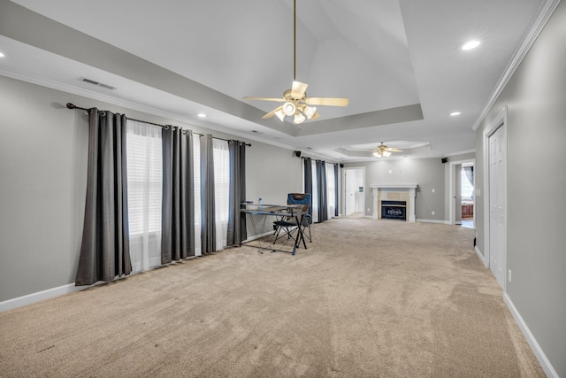 unfurnished living room with carpet flooring, a raised ceiling, ceiling fan, and ornamental molding