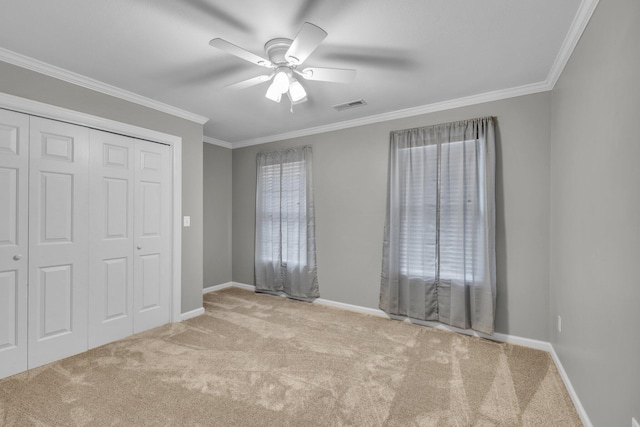 unfurnished bedroom featuring a closet, ceiling fan, crown molding, and light colored carpet