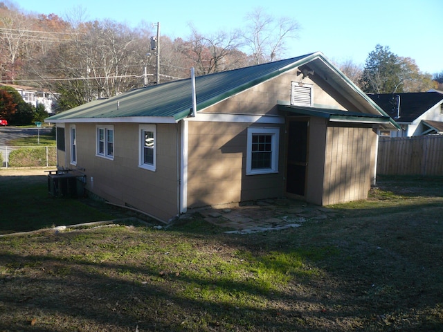 view of property exterior with central AC and a lawn