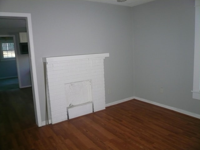 unfurnished living room with dark hardwood / wood-style floors and a brick fireplace