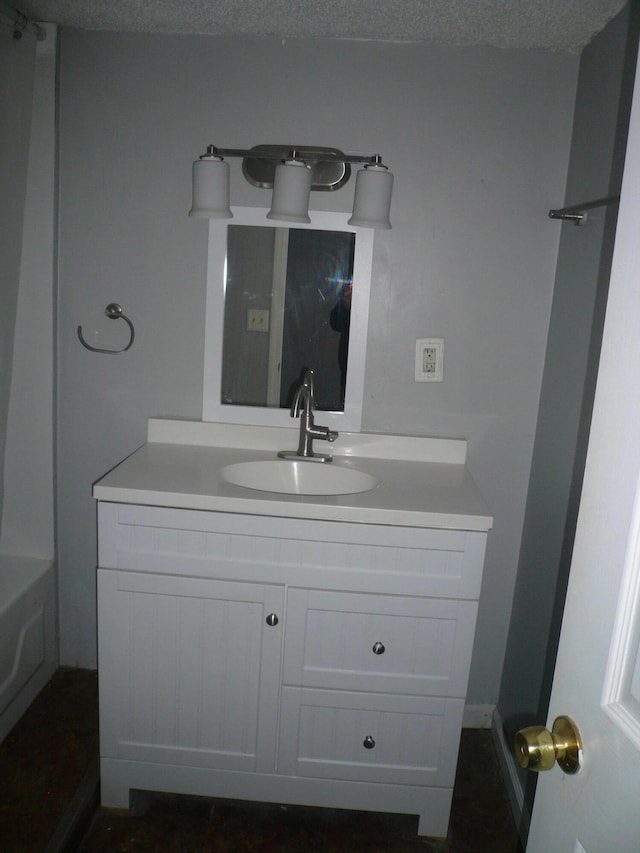 bathroom with a washtub, vanity, and a textured ceiling