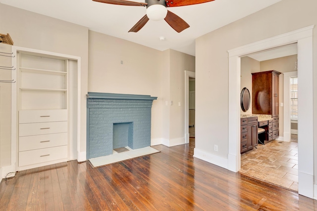 unfurnished living room featuring a fireplace, baseboards, ceiling fan, and hardwood / wood-style floors