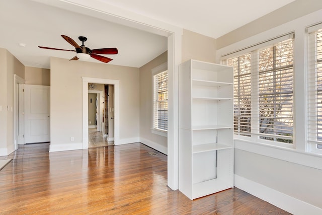 unfurnished room featuring ceiling fan, baseboards, and wood finished floors