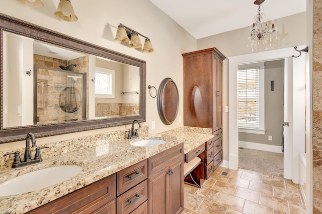 bathroom featuring double vanity, tiled shower, baseboards, and a sink