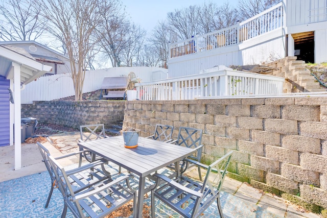 view of patio featuring stairway, outdoor dining area, and fence