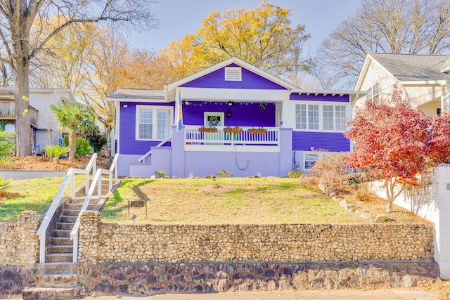 bungalow featuring stairway, a porch, and a front lawn