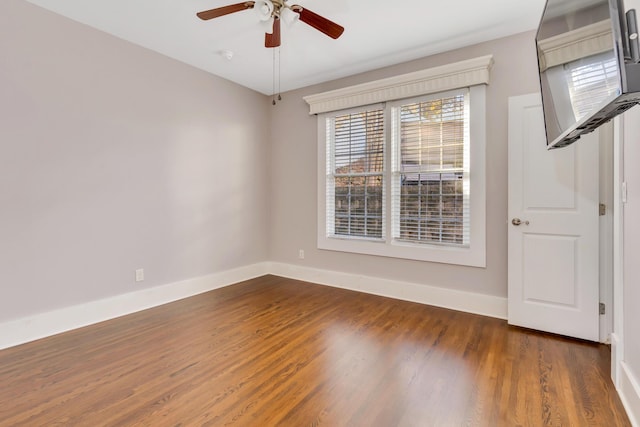 spare room featuring ceiling fan, baseboards, and wood finished floors