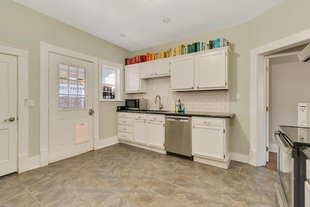 kitchen featuring dark countertops, decorative backsplash, appliances with stainless steel finishes, white cabinets, and a sink