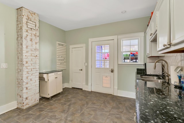 kitchen featuring tasteful backsplash, white cabinets, baseboards, and a sink