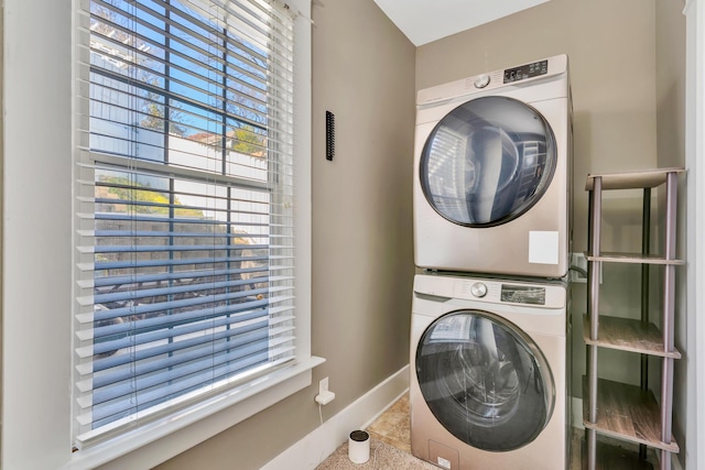 laundry room featuring baseboards, laundry area, and stacked washer / dryer