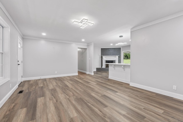 unfurnished living room featuring hardwood / wood-style flooring, crown molding, and a fireplace