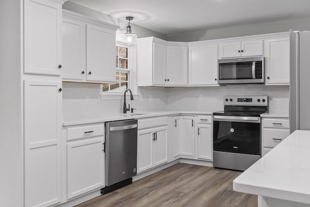 kitchen featuring pendant lighting, stainless steel appliances, white cabinetry, and sink