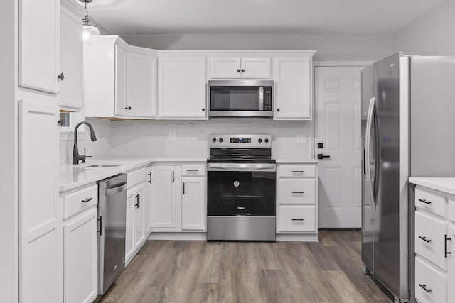 kitchen with pendant lighting, white cabinetry, hardwood / wood-style floors, and appliances with stainless steel finishes