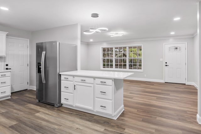 kitchen with stainless steel fridge, ornamental molding, dark wood-type flooring, decorative light fixtures, and white cabinets