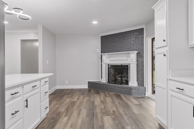 unfurnished living room featuring a fireplace, light hardwood / wood-style floors, ornamental molding, and brick wall