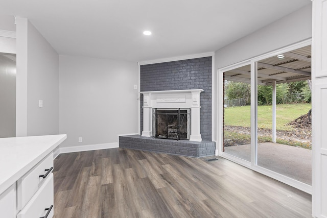 unfurnished living room with wood-type flooring and a brick fireplace