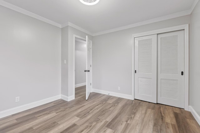 unfurnished bedroom with crown molding, a closet, and light hardwood / wood-style floors