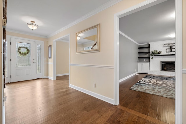 foyer with wood-type flooring, ornamental molding, and a fireplace