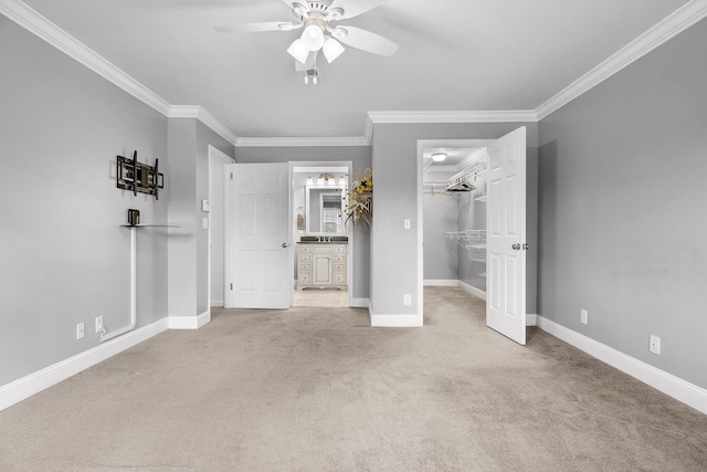 unfurnished bedroom with a walk in closet, light colored carpet, ceiling fan, crown molding, and a closet