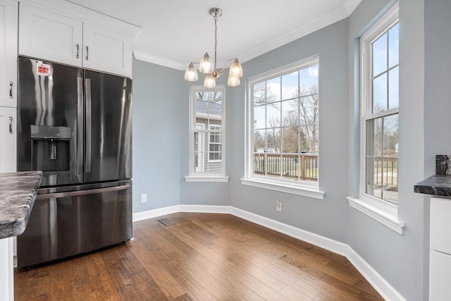 kitchen with dark wood-type flooring, white cabinets, crown molding, stainless steel fridge, and a chandelier