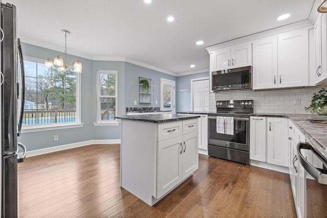 kitchen featuring tasteful backsplash, dark stone countertops, pendant lighting, white cabinets, and appliances with stainless steel finishes