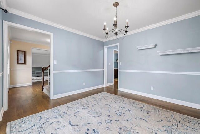 spare room featuring dark hardwood / wood-style flooring, a notable chandelier, and ornamental molding